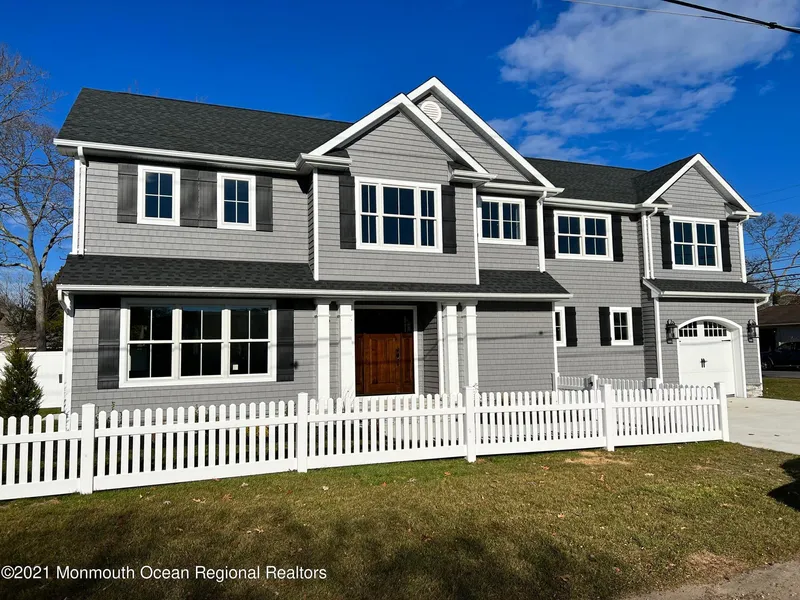 single home with grey single siding, white trim, black shutters, white picket fence, wood front door, covered front entry