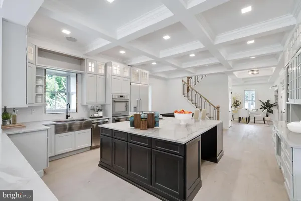 Kitchen with white cabinets, dark wood island, coffered ceiling