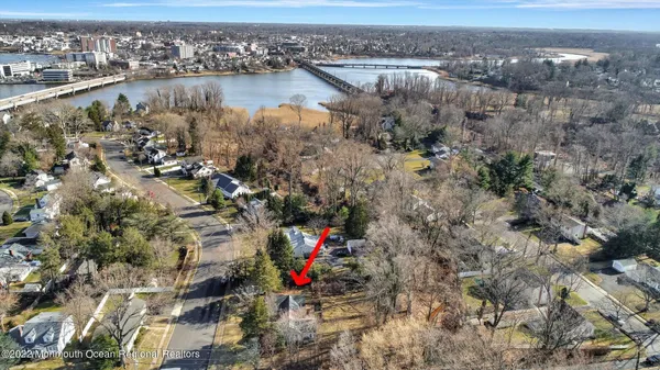aerial view of home on lot with mature trees near water