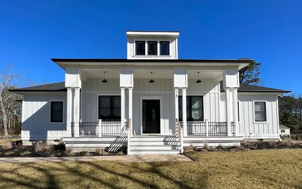 new modern farmhouse home with white siding black trim windows covered front porch