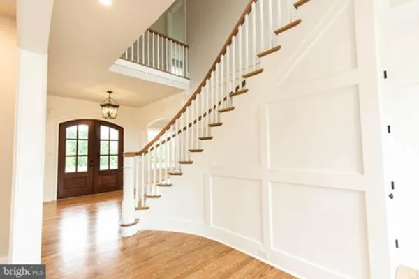 Grand entrance foyer with curved stairway, panelled wainscoting, curve top double entry doors