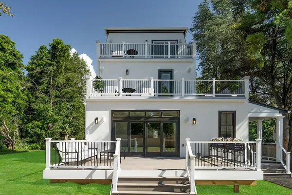 Photo of white, 3 story renovated home with back deck and side porch