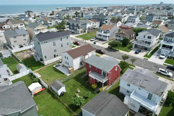 Aerial view of home with red siding near ocean