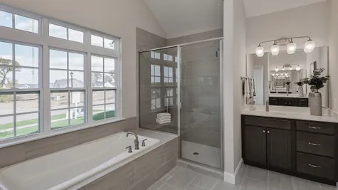 Luxurious Owner's Bath with separate vanities, soaker tub, and large walk in shower