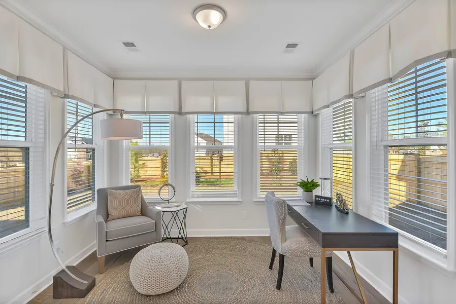 Sunroom office with windows and desk in new construction home by Mungo Homes
