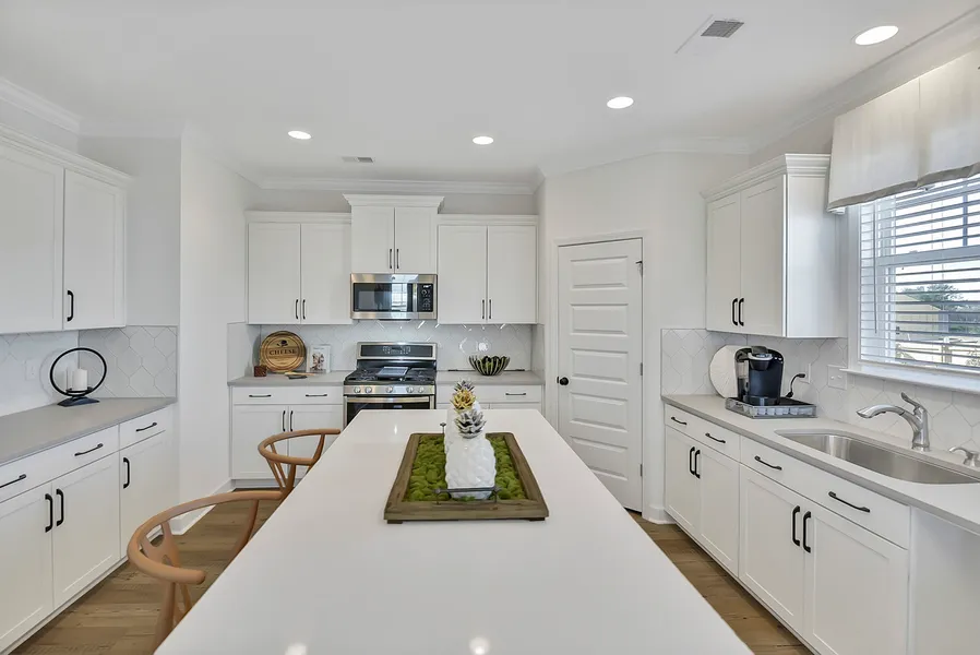 White kitchen with wood barstools and big island and corner pantry in new construction home by Mungo Homes