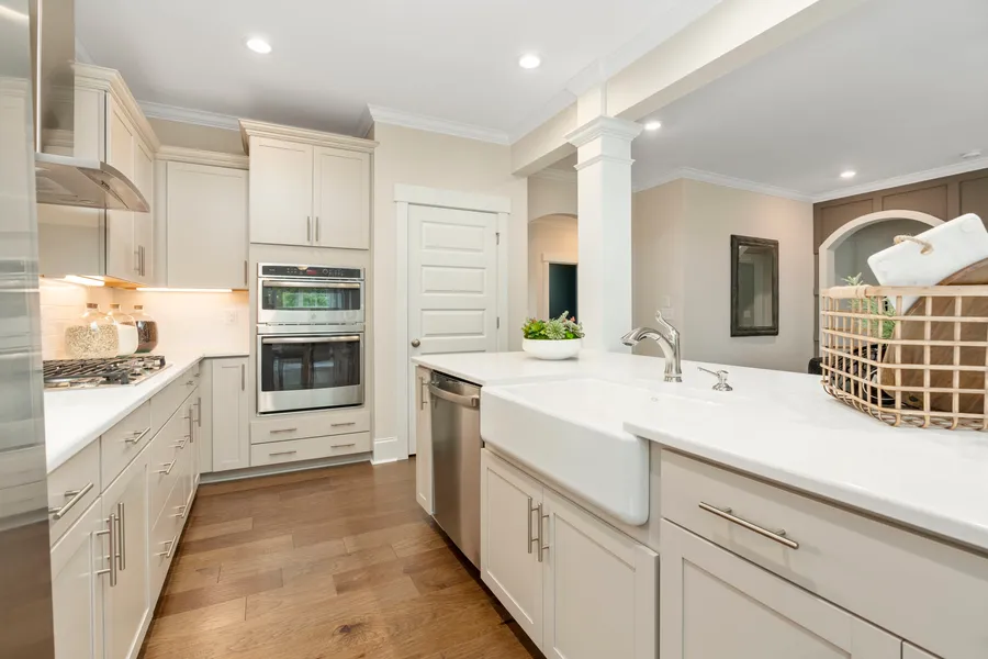 Kitchen with cream cabinets and white countertops with a farm house sink in new construction home by Mungo Homes