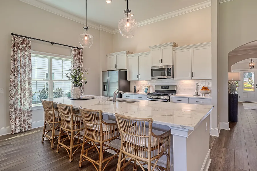 Open kitchen with large island and stainless steel appliances in new construction Mungo Home