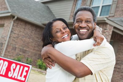 Homeowners embracing in front of the home they're selling