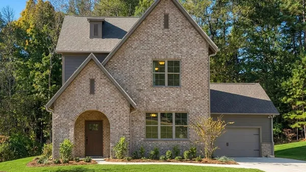 Multi-story brick exterior featuring a recessed arched entryway, steeply pitched rooflines, and a side-load garage