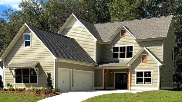 Two-story exterior featuring horizontal siding, a gabled roofline, a two-car garage, and a covered front entry with timber accents