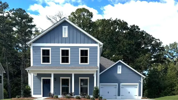 Two-story exterior featuring blue horizontal and vertical siding, a covered front porch with square columns, and an attached two-car garage