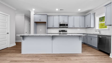 Interior photo of an open concept kitchen with gray cabinets and white backsplash