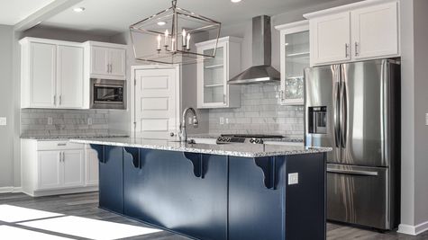 Interior view of kitchen with white cabinets and dark blue island