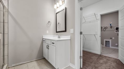 Interior photo of bathroom with white cabinets and walk in closet connected to laundry room
