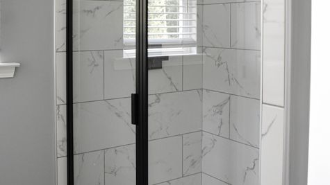Interior view of a marbled shower with a glass frame door