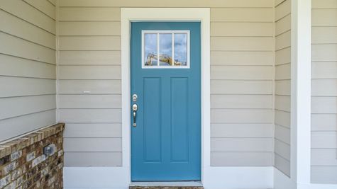 Exterior photo of front door beige siding, brick accents, and a blue front door