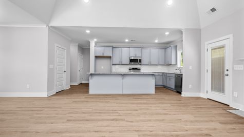Interior photo of kitchen with grey cabinets and white backsplash with a marble countertop
