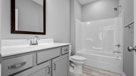 Interior view of secondary bathroom with grey cabinets and white countertop and tub/shower combo