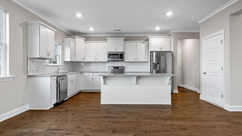 Interior photo of an all white open concept kitchen with stainless steel appliances