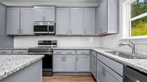 Interior photo of kitchen with grey cabinets and white backsplash