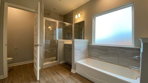 interior photo of all grey master bathroom with separate tub and tile shower