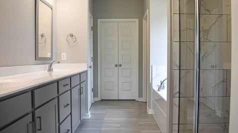Interior view of Bathroom with marble tile shower, separate tub, and grey cabinets