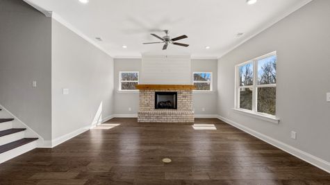 Interior photo of a living room with upgraded half brick and shiplap fireplace with a cedar mantle