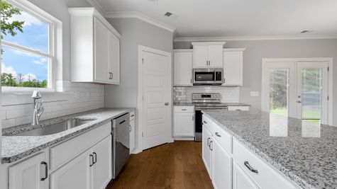 Interior view of Kitchen with white cabinets, white counter tops, & chrome accents