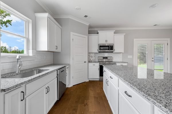 Interior view of Kitchen with white cabinets, white counter tops, & chrome accents