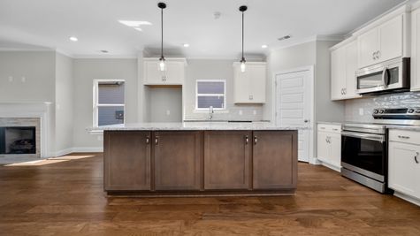 Interior view of kitchen with two toned white cabinets and large dark wood island