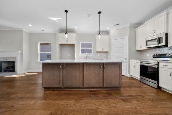 Interior view of kitchen with two toned white cabinets and large dark wood island