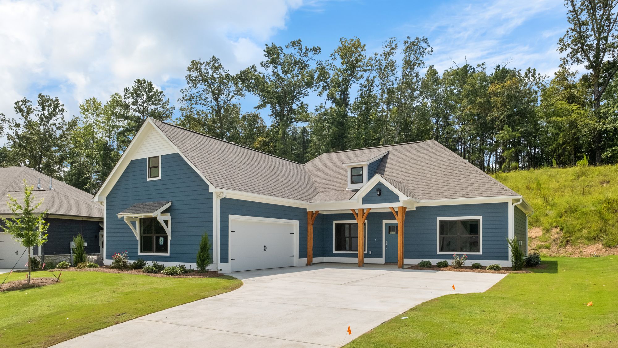 Exterior photo of a Bragg floorplan with blue siding, cedar accents, and a blue front door