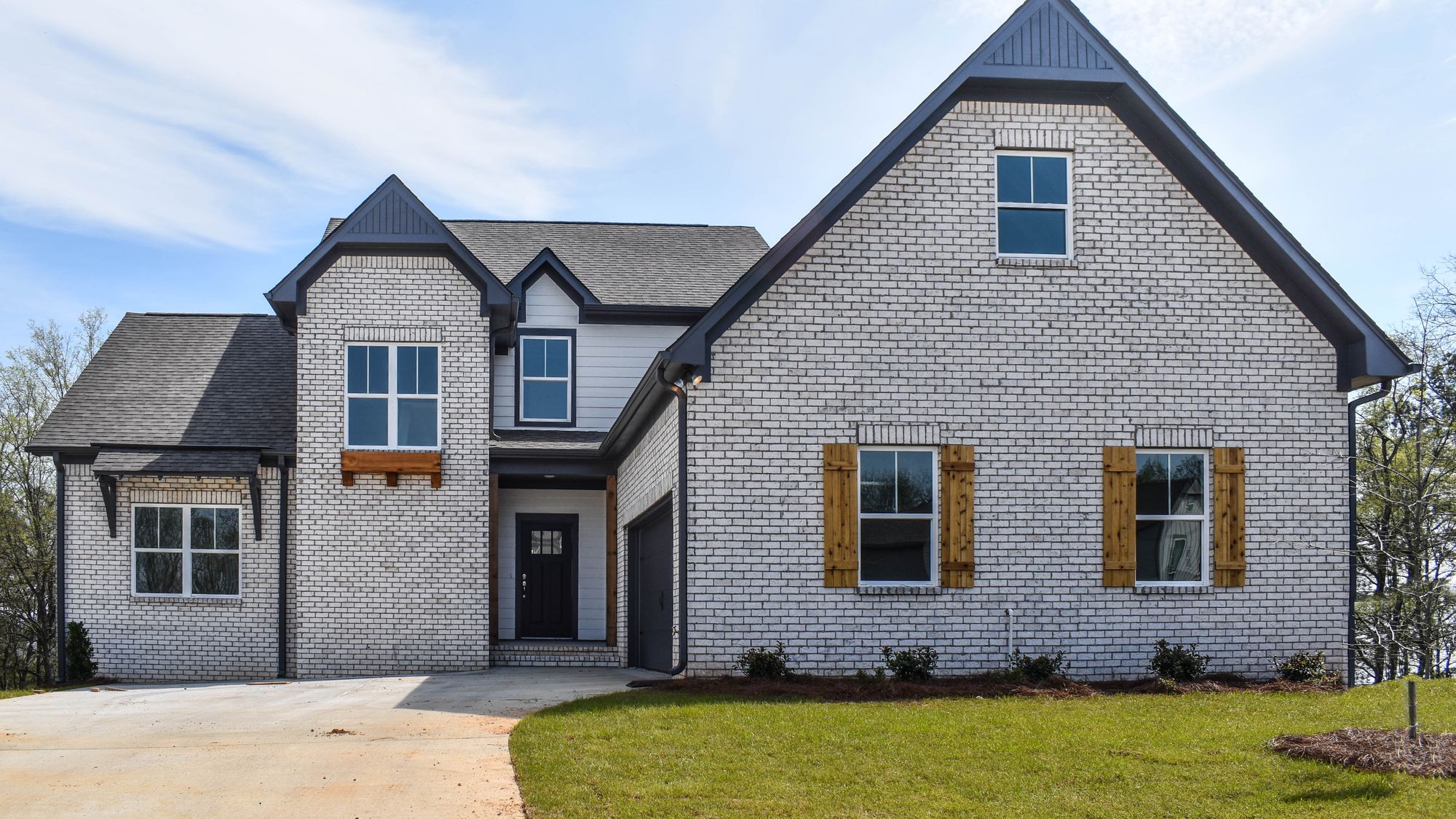Exterior photo of white brick house with cedar accents and a dark front door