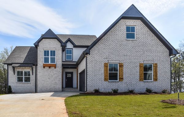 Exterior photo of white brick house with cedar accents and a dark front door
