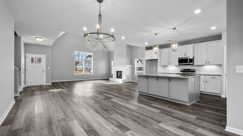 Interior view of living area with open concept floorplan with white kitchen cabinets and dark grey island