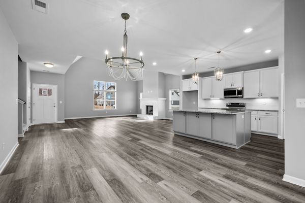 Interior view of living area with open concept floorplan with white kitchen cabinets and dark grey island