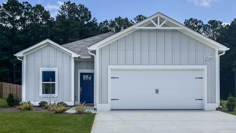 Exterior view of 1 level house with blue grey siding and white trim, dark blue front door