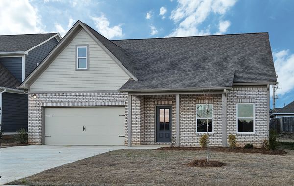 Exterior photo of 1 level home with half white brick and tan vinyl siding with grey trim