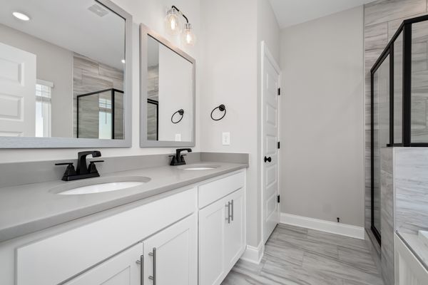 Interior  view of bathroom with white cabinets black accents and grey counter tops