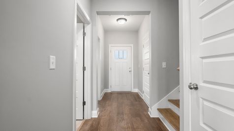 Interior photo of hallway from foyer with gray painted walls and hardwood flooring