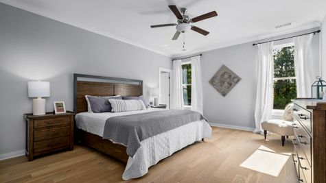 Interior photo of bedroom with gray painted walls, hardwood flooring, and big windows