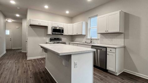 interior photo of kitchen with white cabinets, white backsplash and white countertops