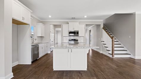 Interior photo of an all white open concept kitchen with stainless steel appliances