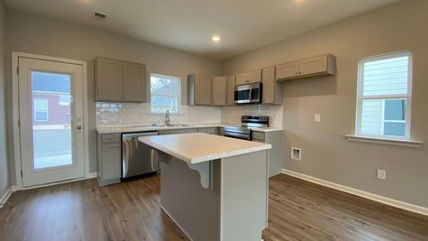 interior photo of kitchen with grey cabinets and white backsplash and countertops