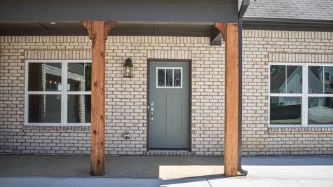 Exterior view of green front door with white brick and cedar posts
