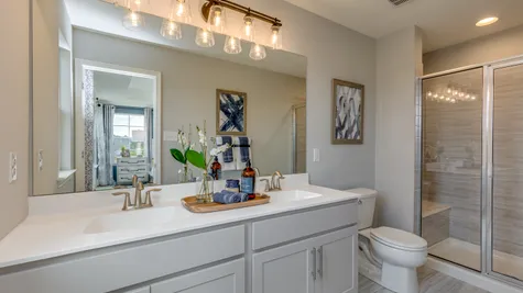 The owner's bathroom shown with large mirror over a double sink and gold accent decor.