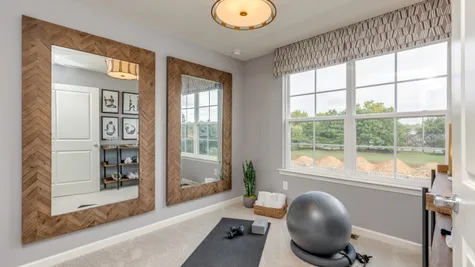 3rd floor townhome bedroom used as an exercise room with large window and two full length mirrors.