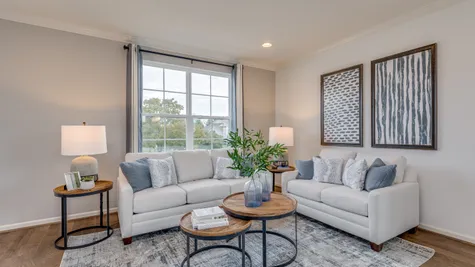 A cozy living room area shown with a large white couch, love seat and ample coffee table space.