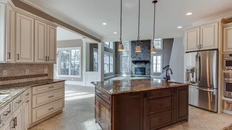 Stoneleigh Kitchen with center island, pendant lights over island, tile floor, granite counters, light color cabinets.